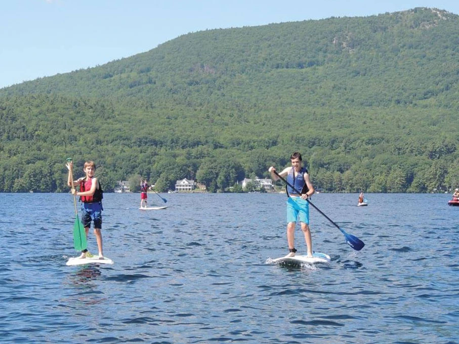 Two boys paddleboarding on Lake Winnipesaukee