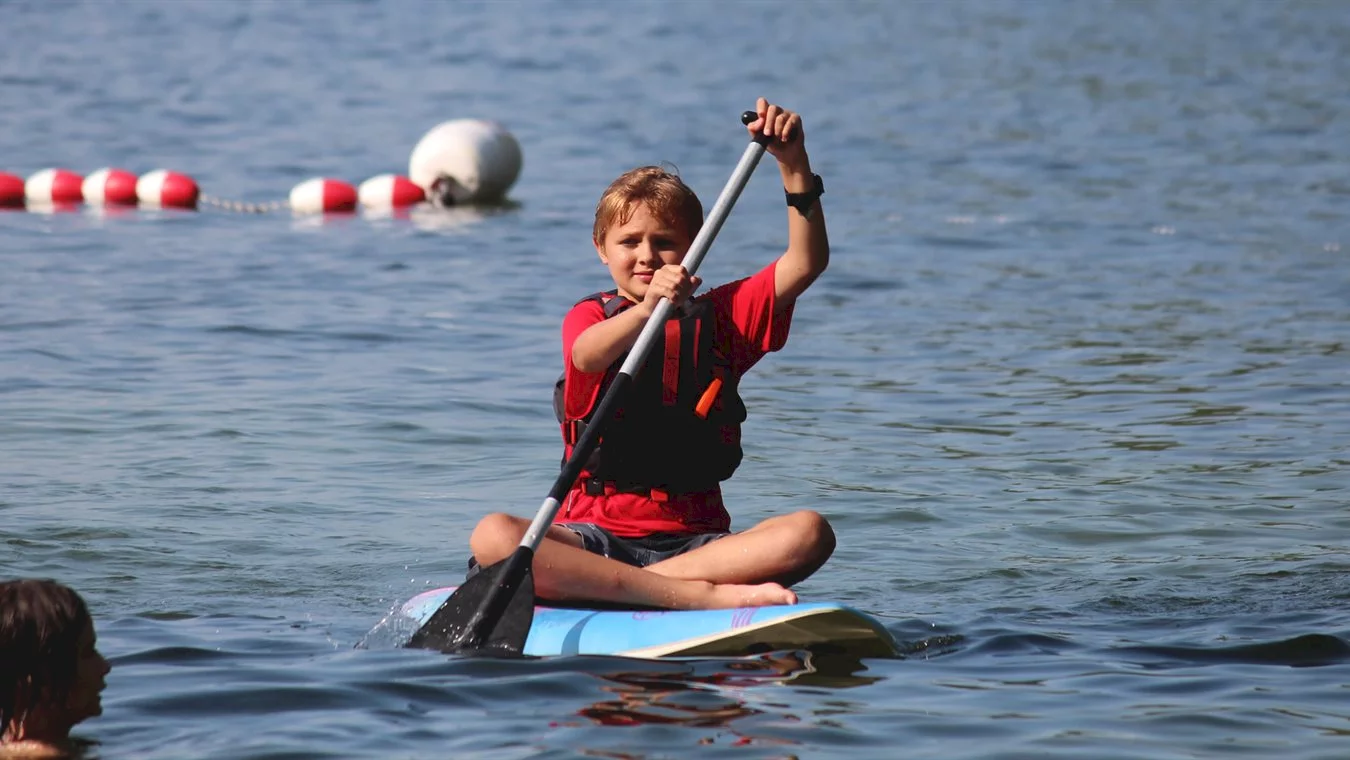 Boy paddle boarding on Lake Winnipesaukee