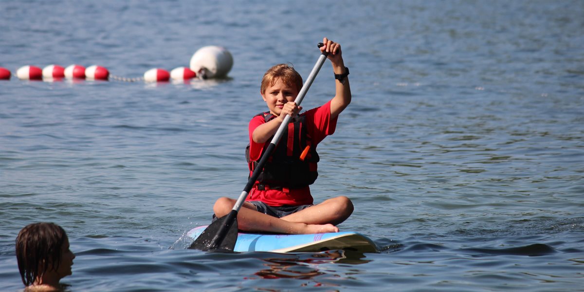 Boy paddle boarding on Lake Winnipesaukee