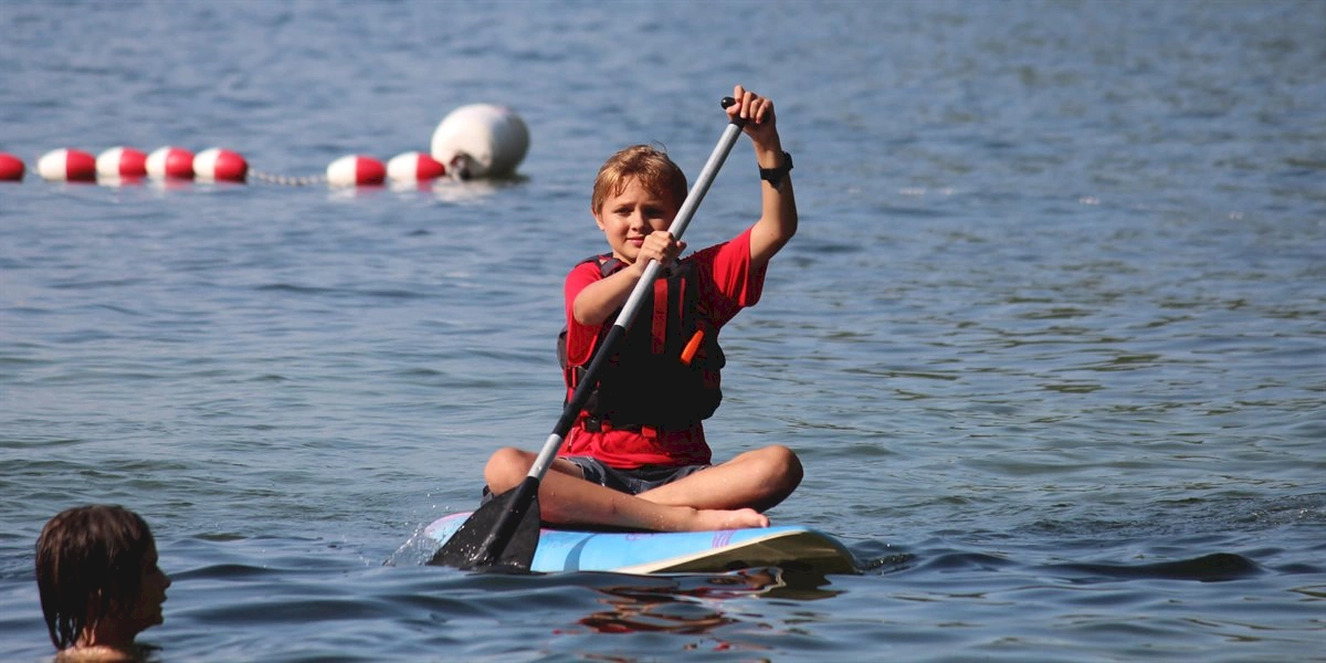 Boy paddle boarding on Lake Winnipesaukee