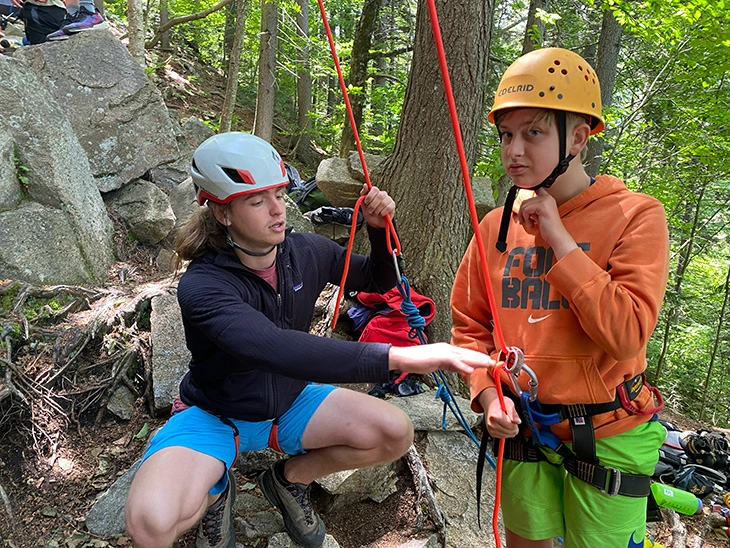 Boy learning to rock climb with Kabeyun camp counselor 