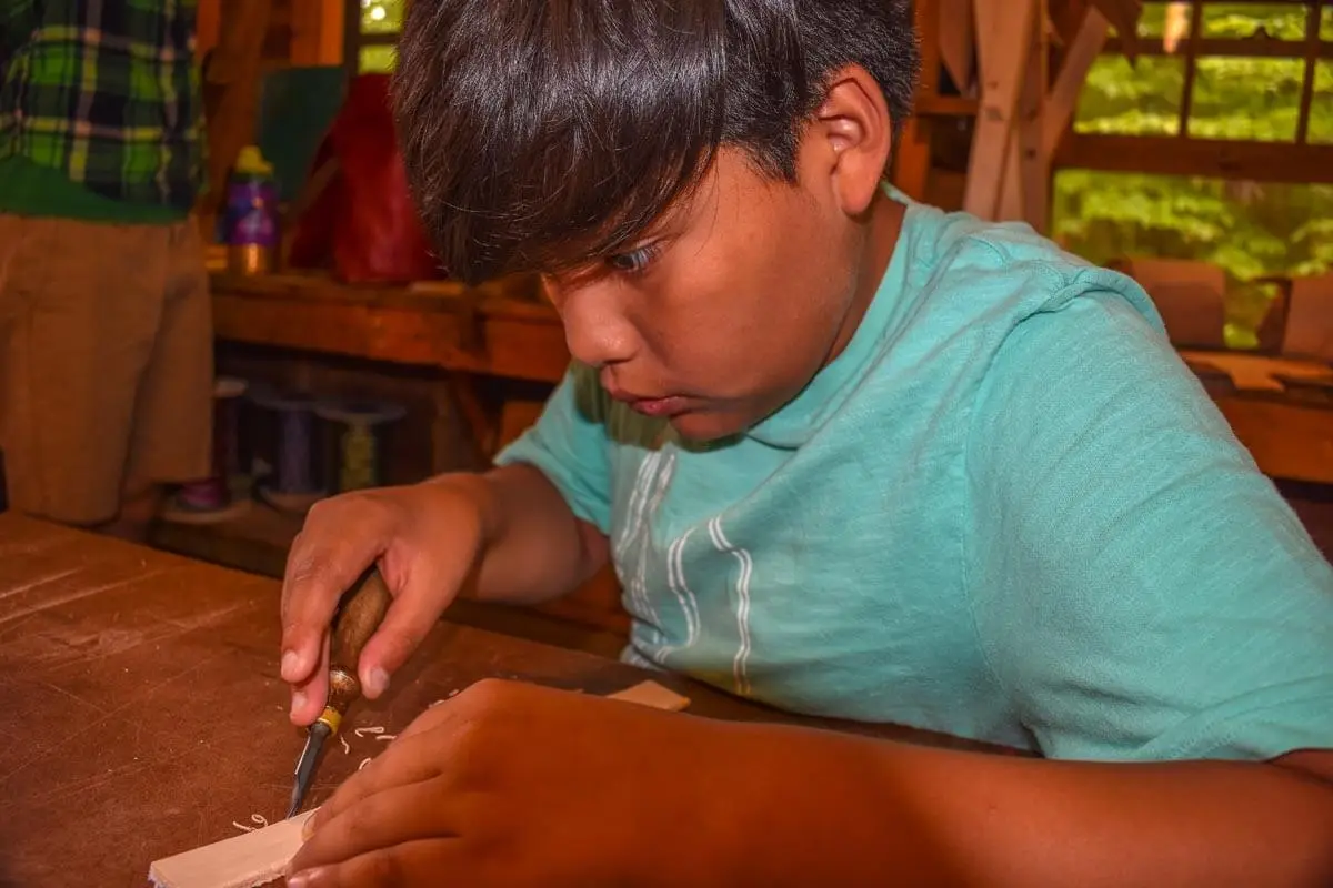 Boy creating a leather pouch during leather working class 