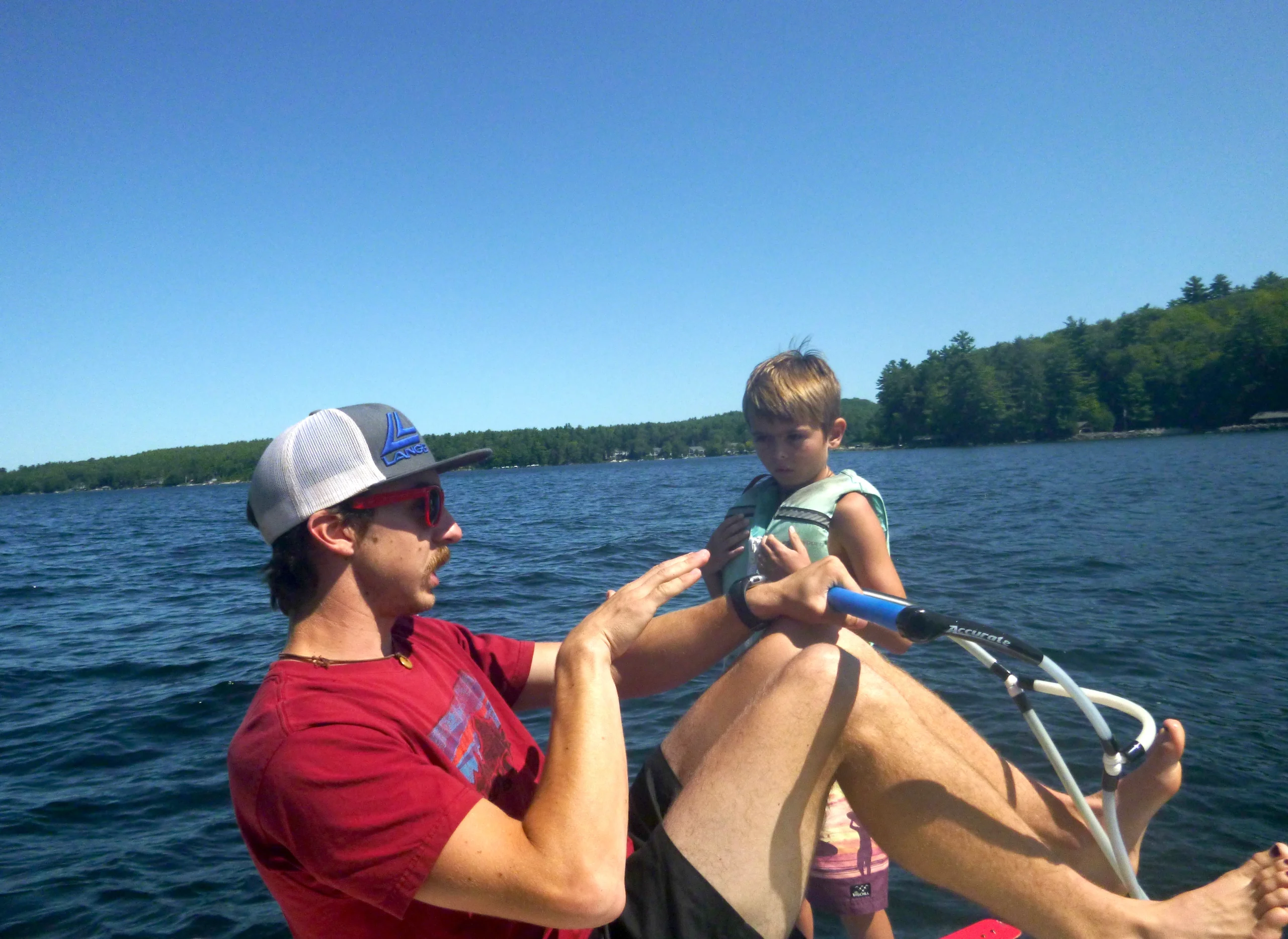 Camp counselor teaching camper how to wake board